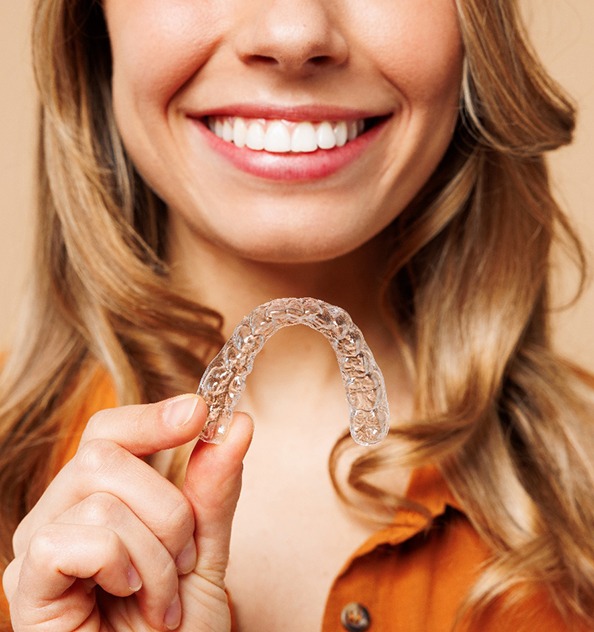 Young woman holding a SureSmile aligner