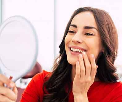 a patient checking her new dental implants with a mirror