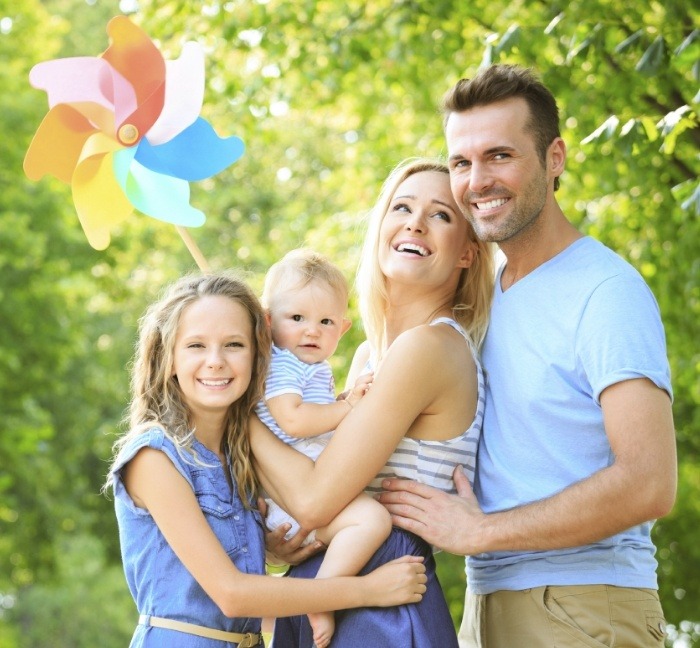 Family of four smiling outdoors after dental services in Waverly